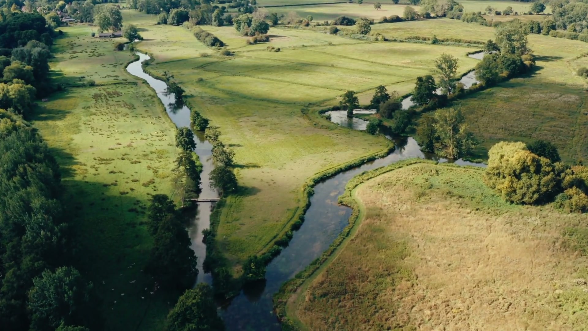Aerial drone shot of a river through fields
